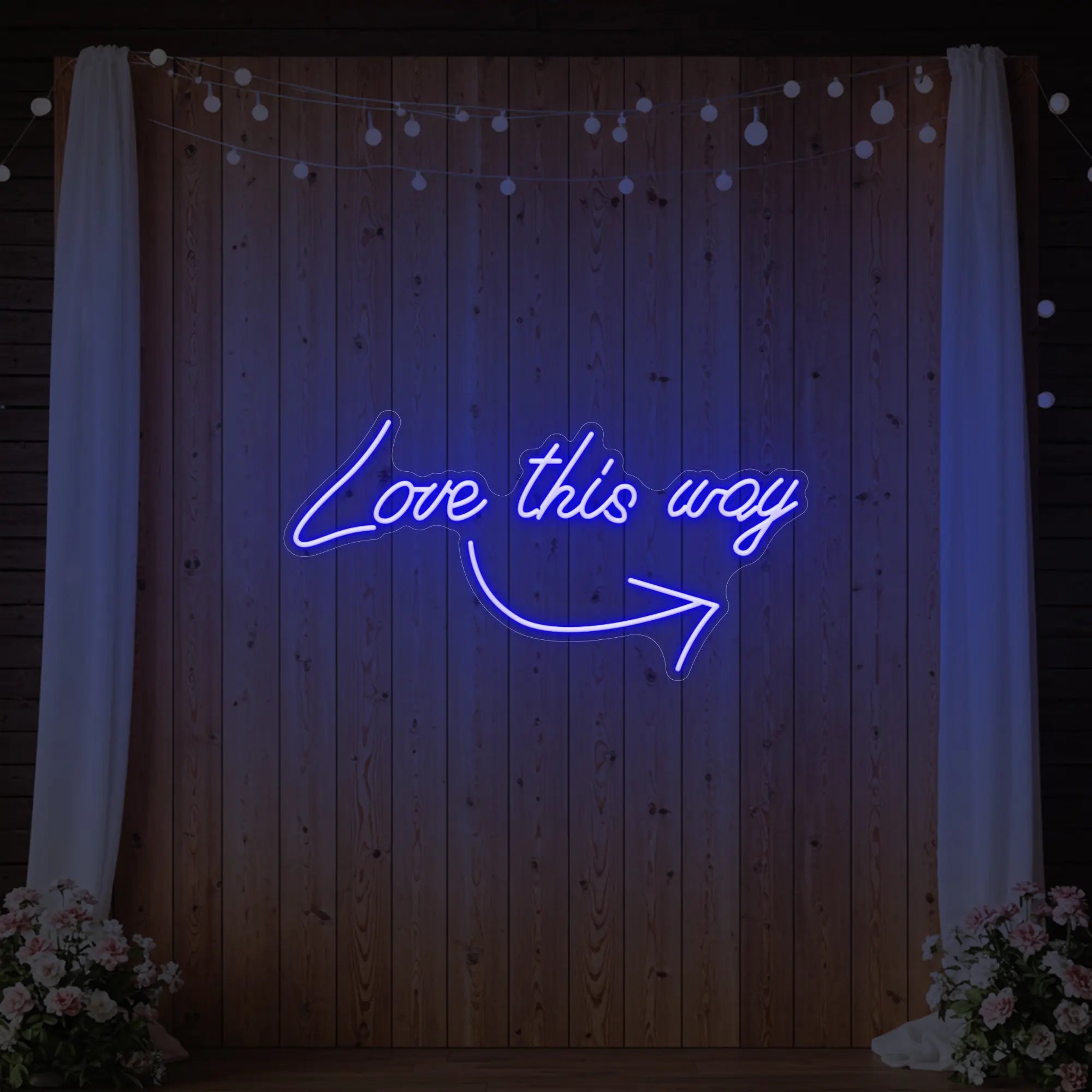 Photo of the 'Love This Way' neon sign glowing in deep blue against a styled interior wall.