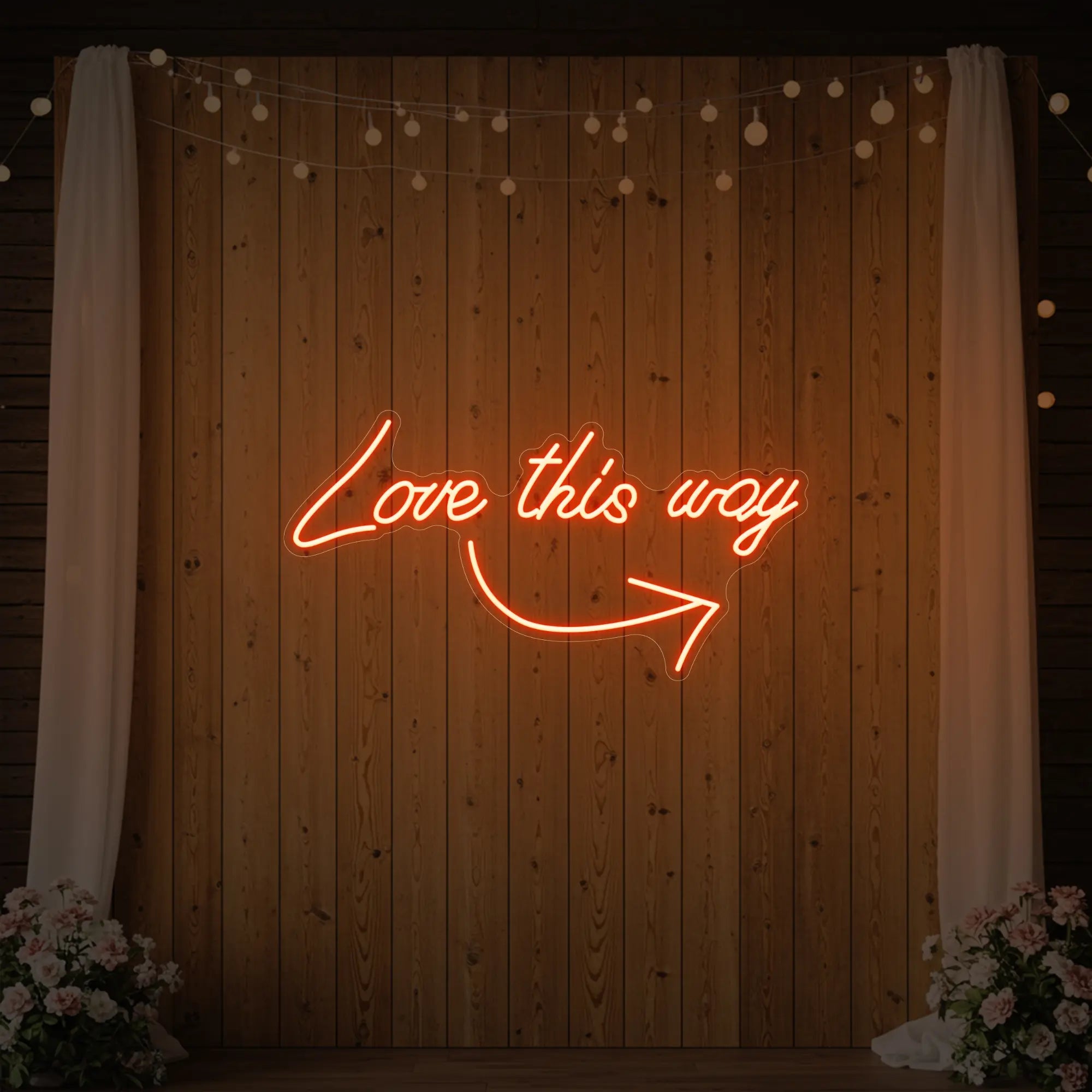 Photo of the 'Love This Way' neon sign glowing in golden yellow against a styled interior wall.