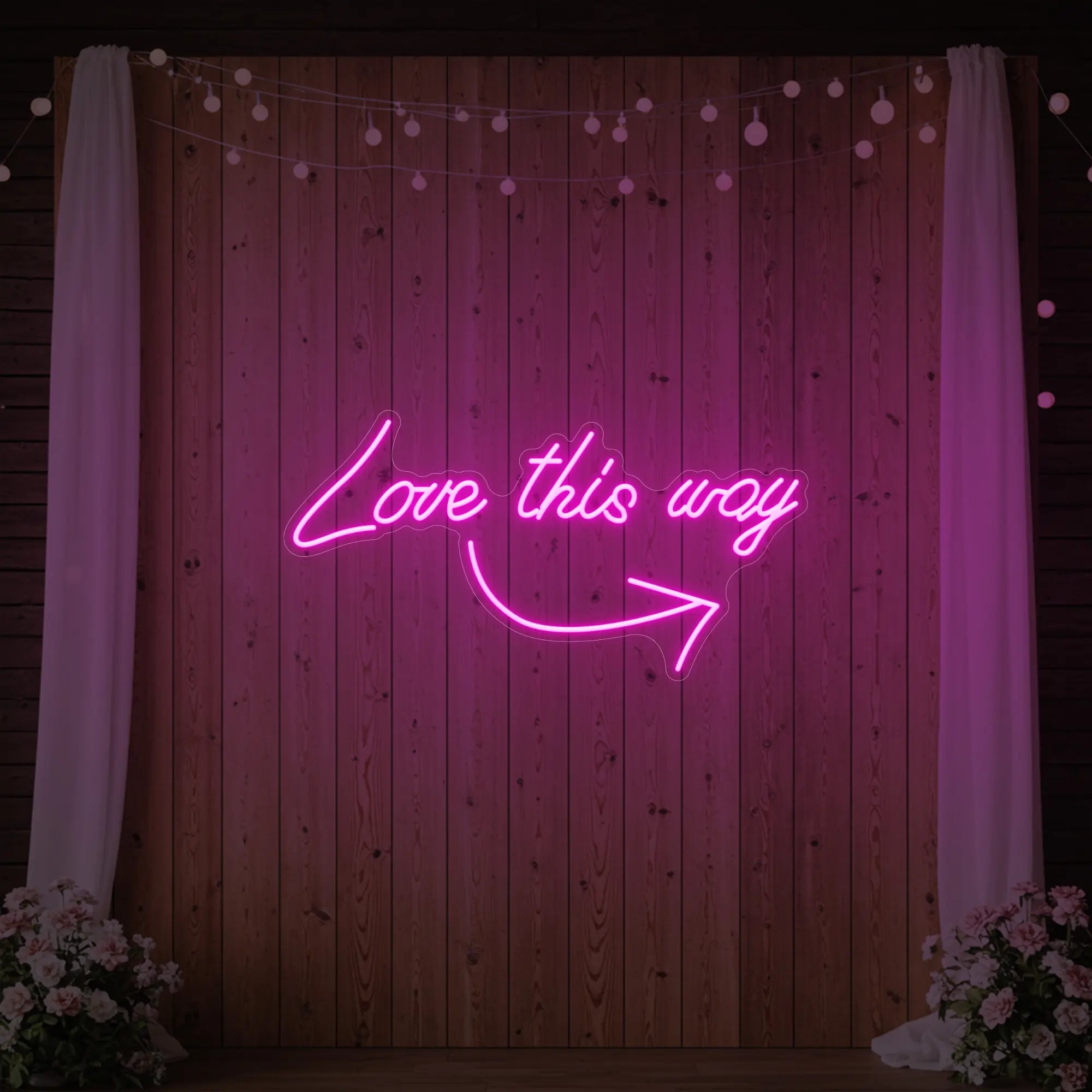 Photo of the 'Love This Way' neon sign glowing in light pink against a styled interior wall.