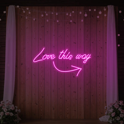 Photo of the 'Love This Way' neon sign glowing in light pink against a styled interior wall.