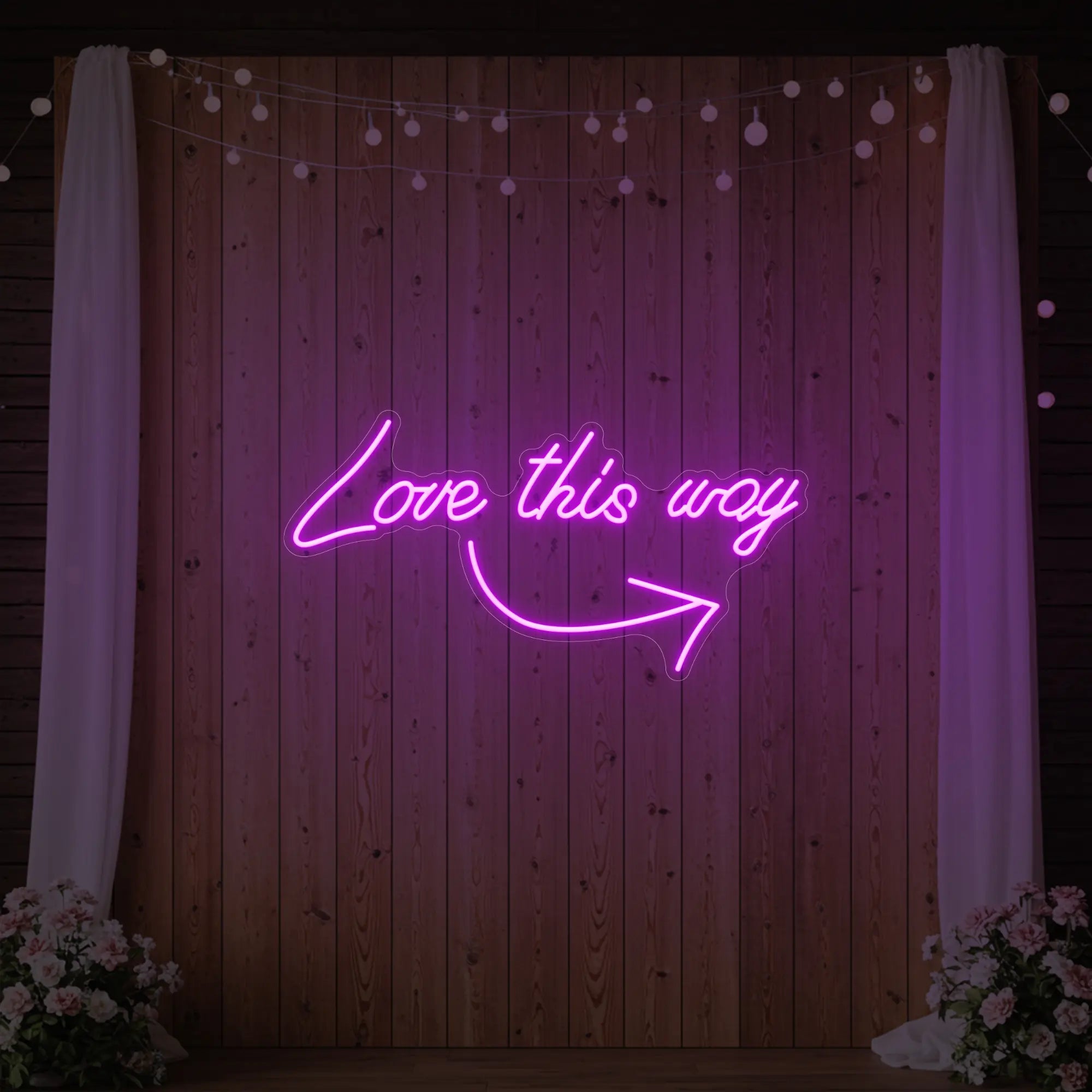 Photo of the 'Love This Way' neon sign glowing in deep pink against a styled interior wall.