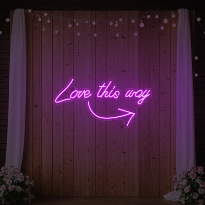 Photo of the 'Love This Way' neon sign glowing in deep pink against a styled interior wall.