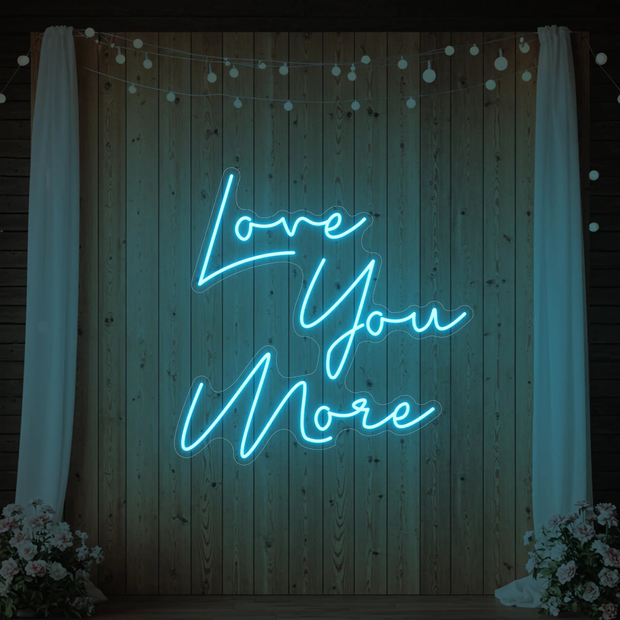 Photo of the 'Love You More' neon sign glowing in ice blue against a styled interior wall.