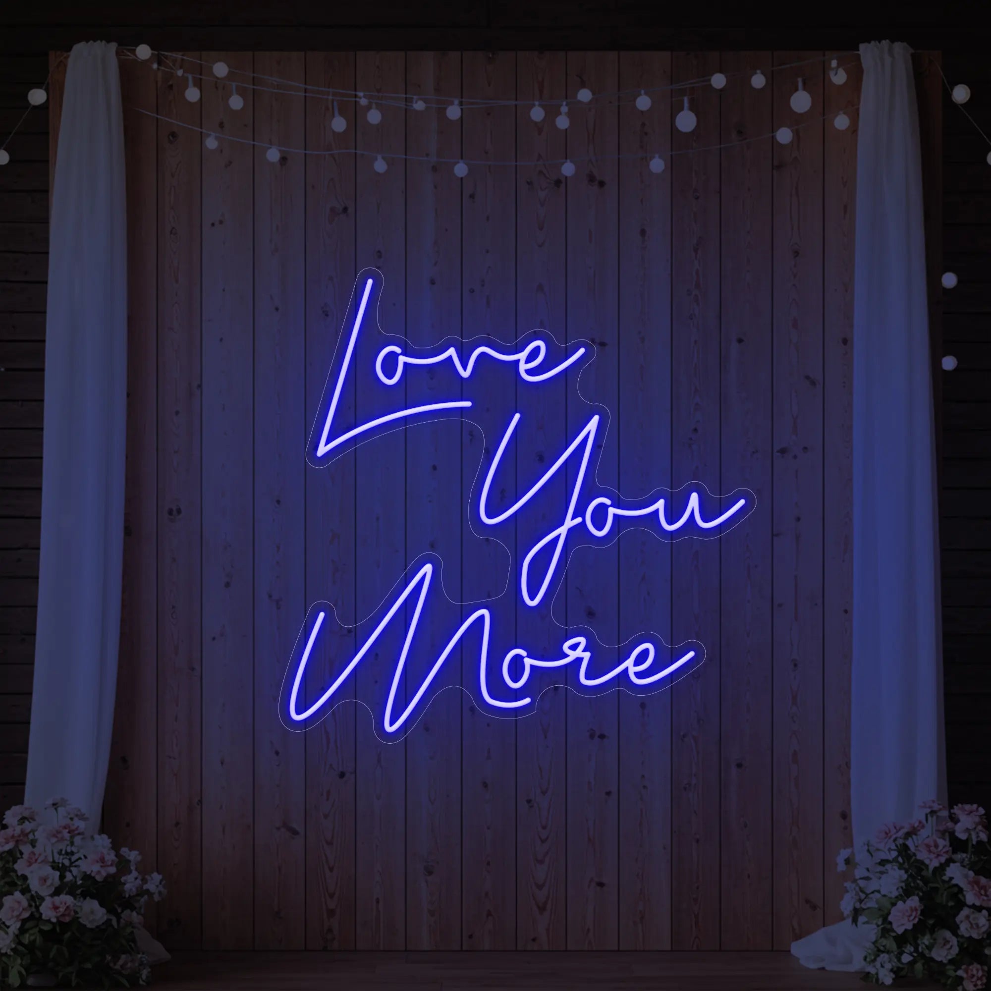 Photo of the 'Love You More' neon sign glowing in deep blue against a styled interior wall.