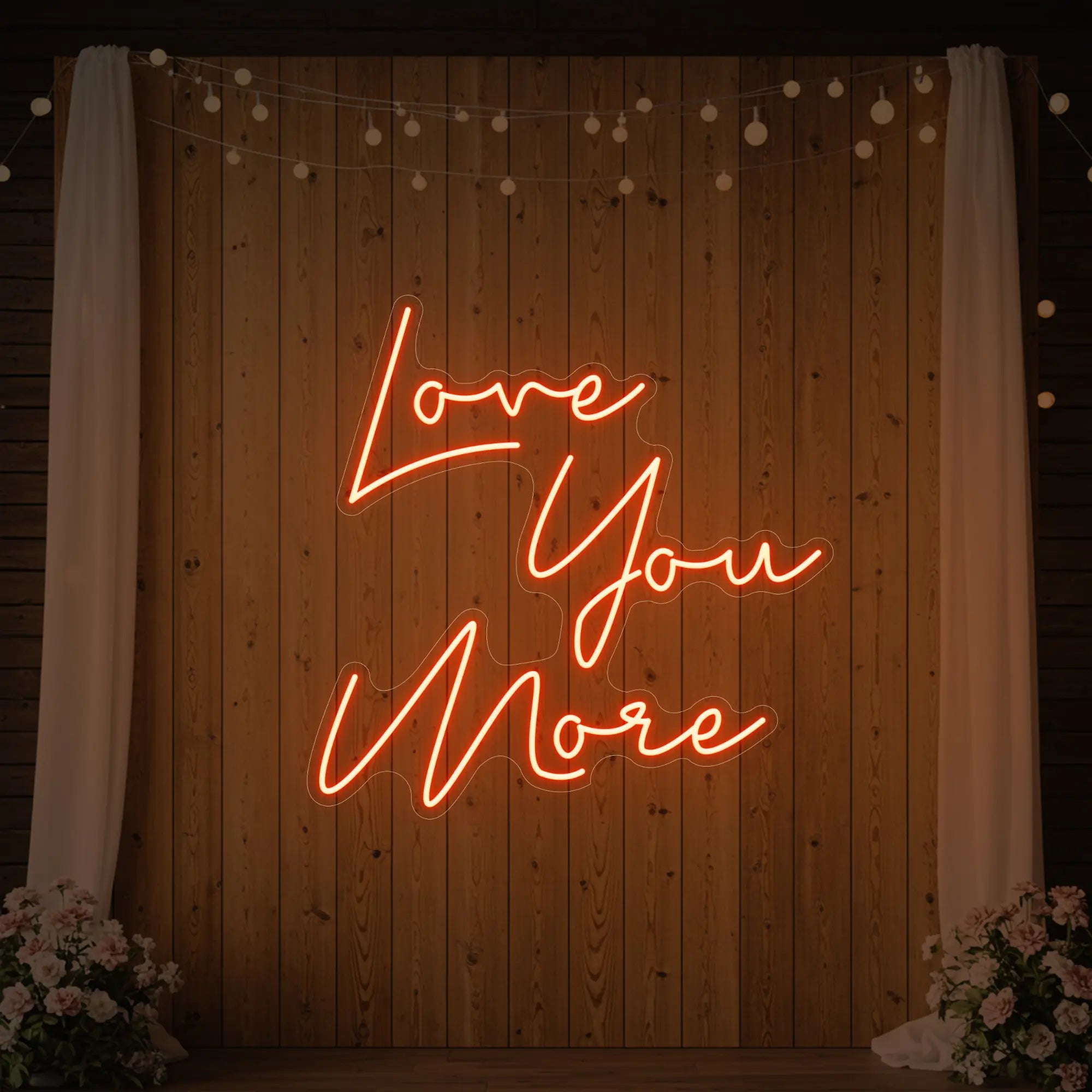 Photo of the 'Love You More' neon sign glowing in golden yellow against a styled interior wall.