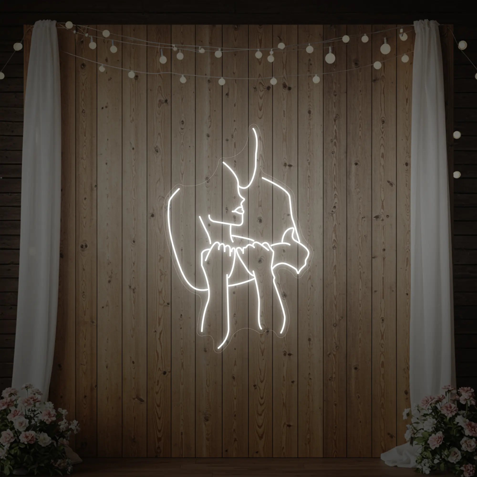 Photo of the 'Lovers Holding Each Other' neon sign glowing in cool white against a styled interior wall.