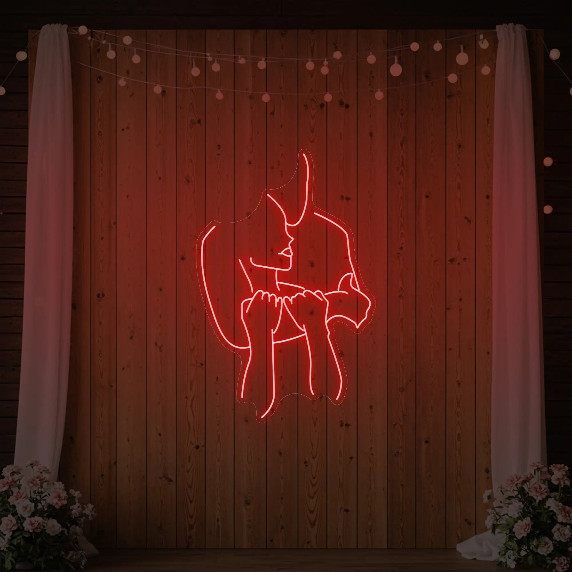 Photo of the 'Lovers Holding Each Other' neon sign glowing in red against a styled interior wall.