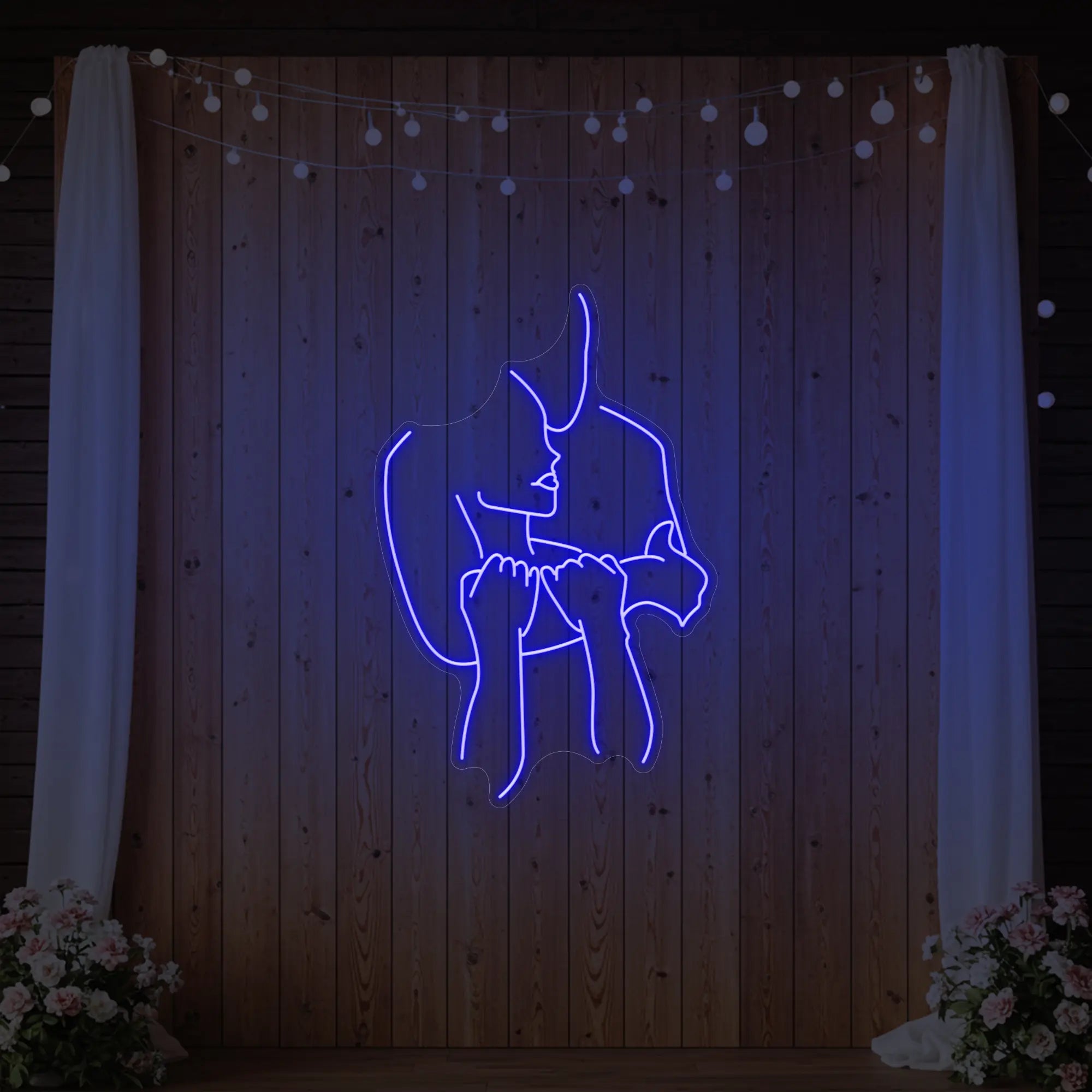 Photo of the 'Lovers Holding Each Other' neon sign glowing in deep blue against a styled interior wall.