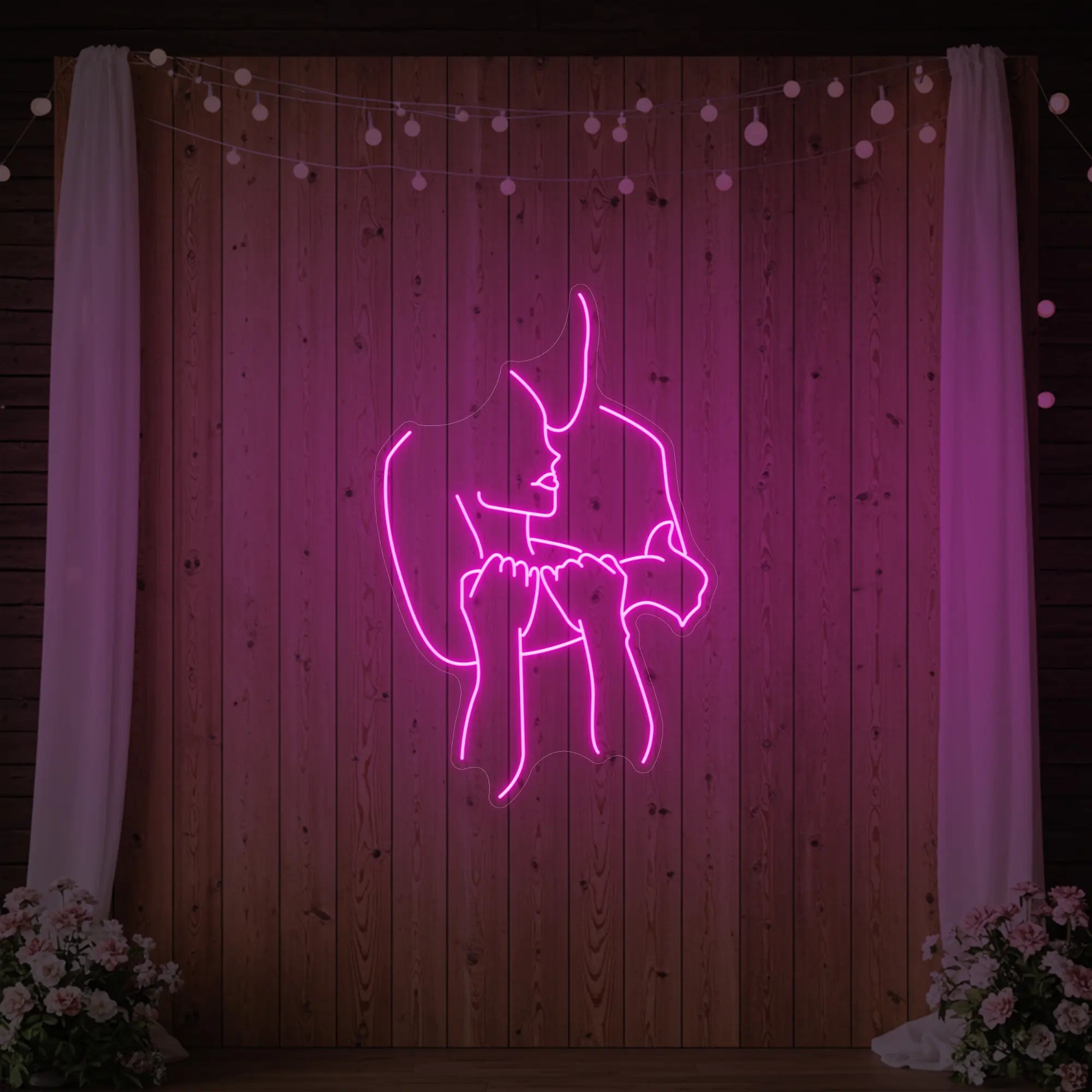 Photo of the 'Lovers Holding Each Other' neon sign glowing in light pink against a styled interior wall.
