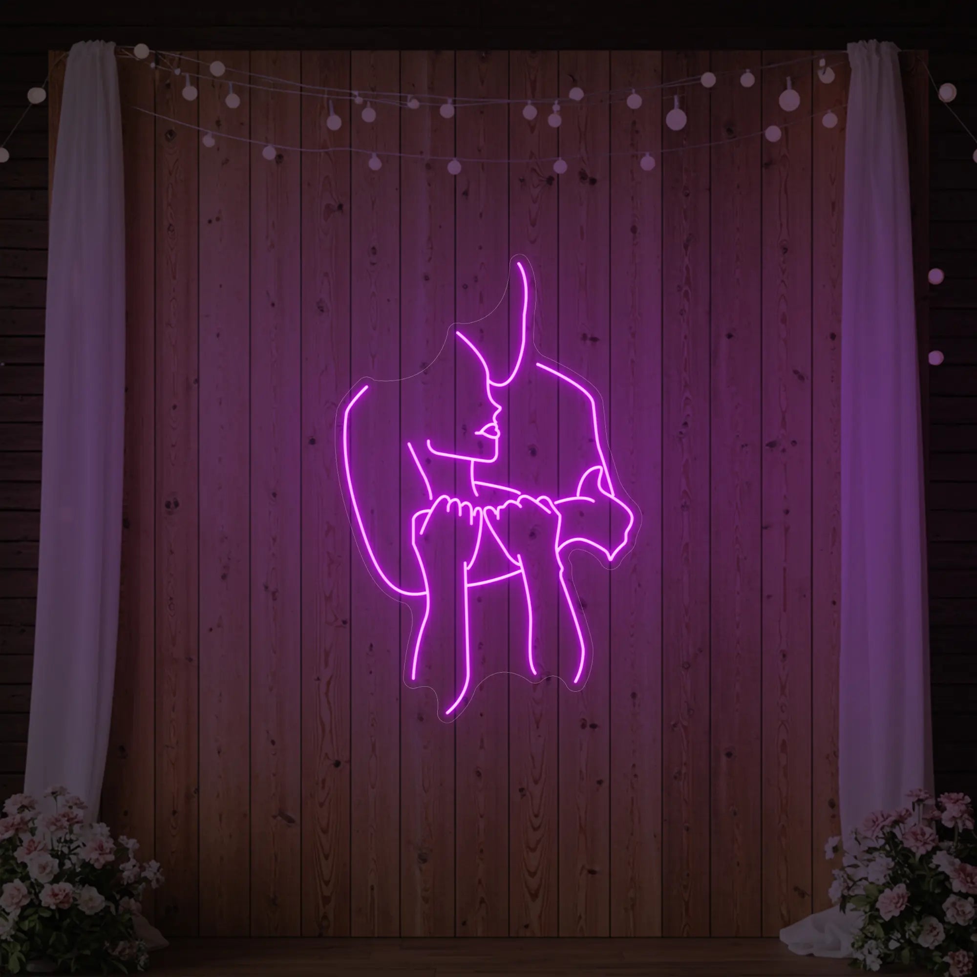 Photo of the 'Lovers Holding Each Other' neon sign glowing in deep pink against a styled interior wall.