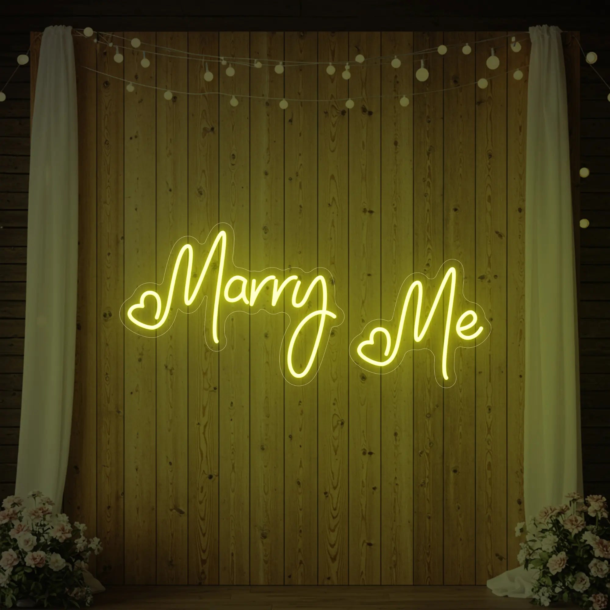 Photo of the 'Marry Me' neon sign glowing in lemon yellow against a styled interior wall.
