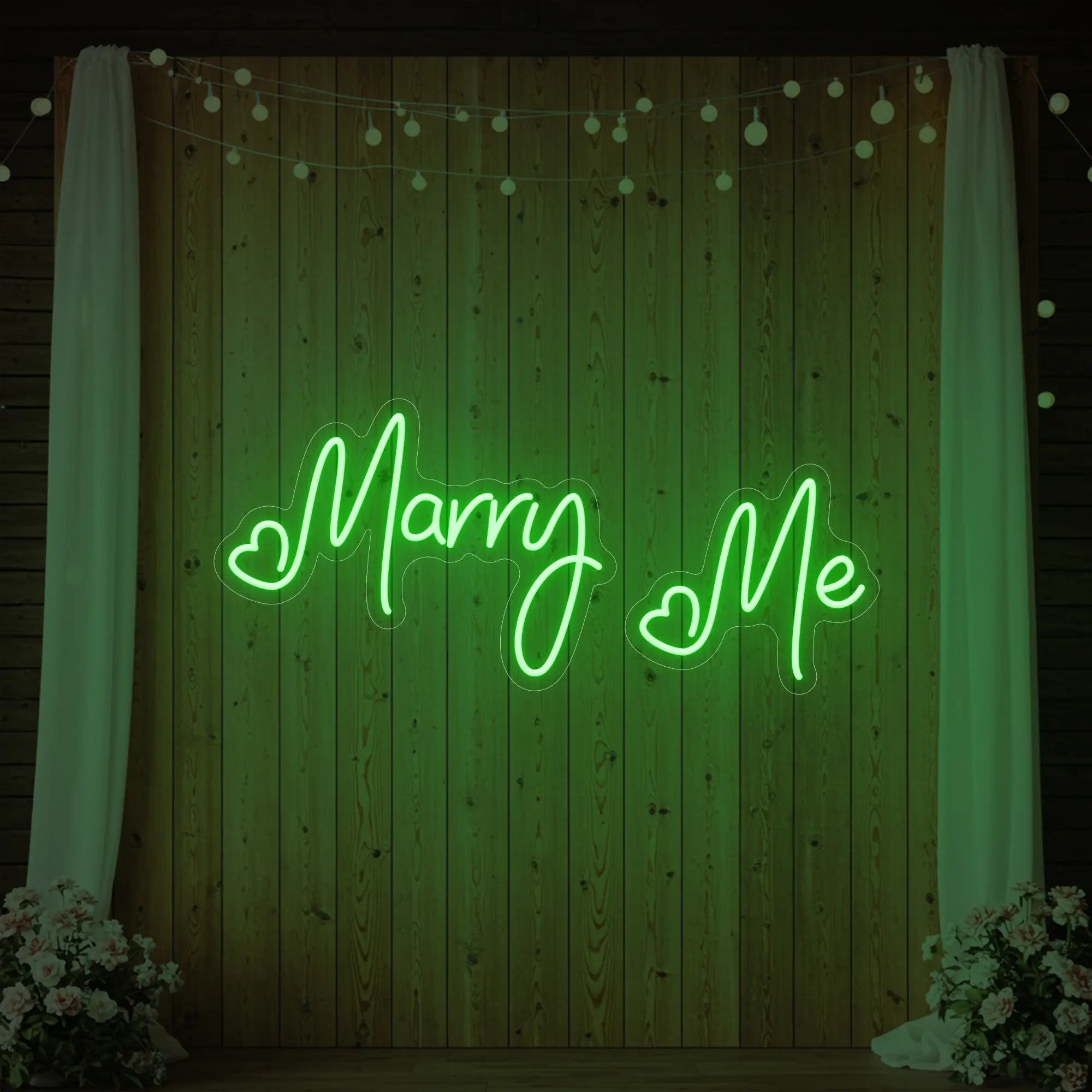 Photo of the 'Marry Me' neon sign glowing in green against a styled interior wall.