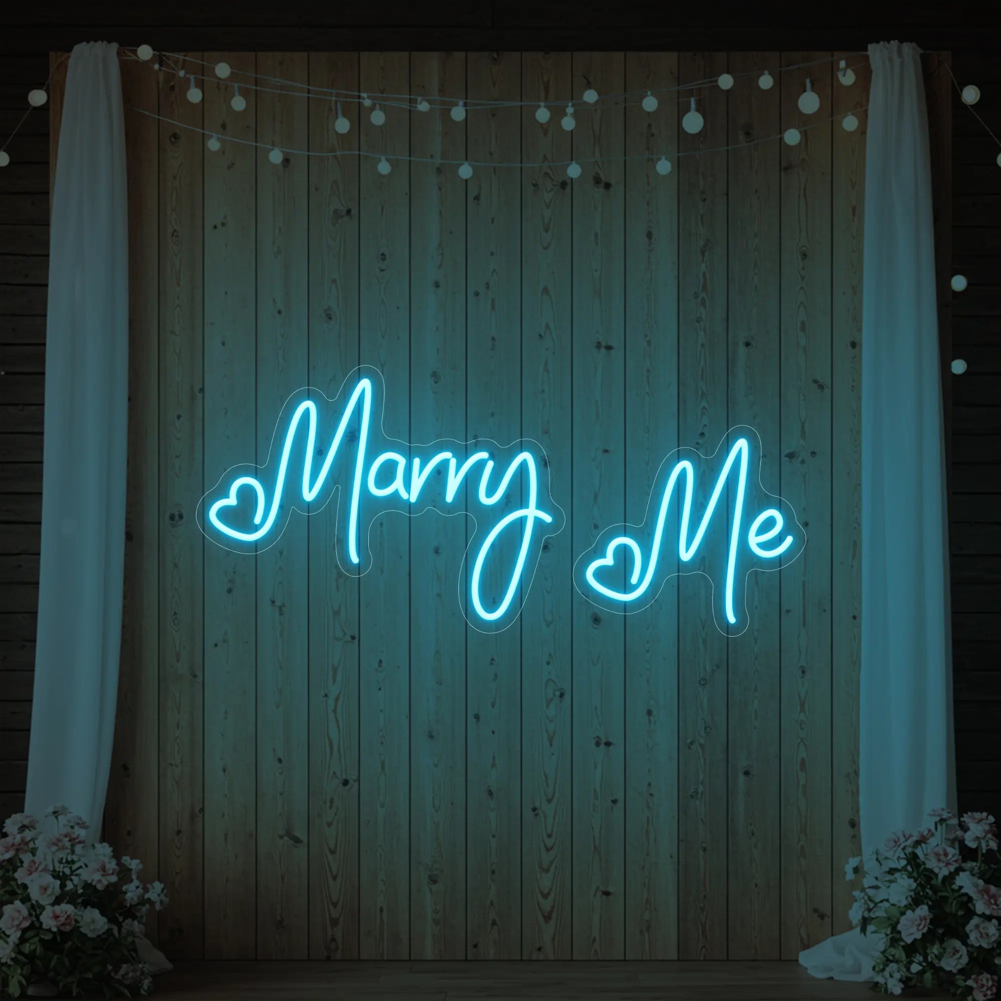 Photo of the 'Marry Me' neon sign glowing in ice blue against a styled interior wall.