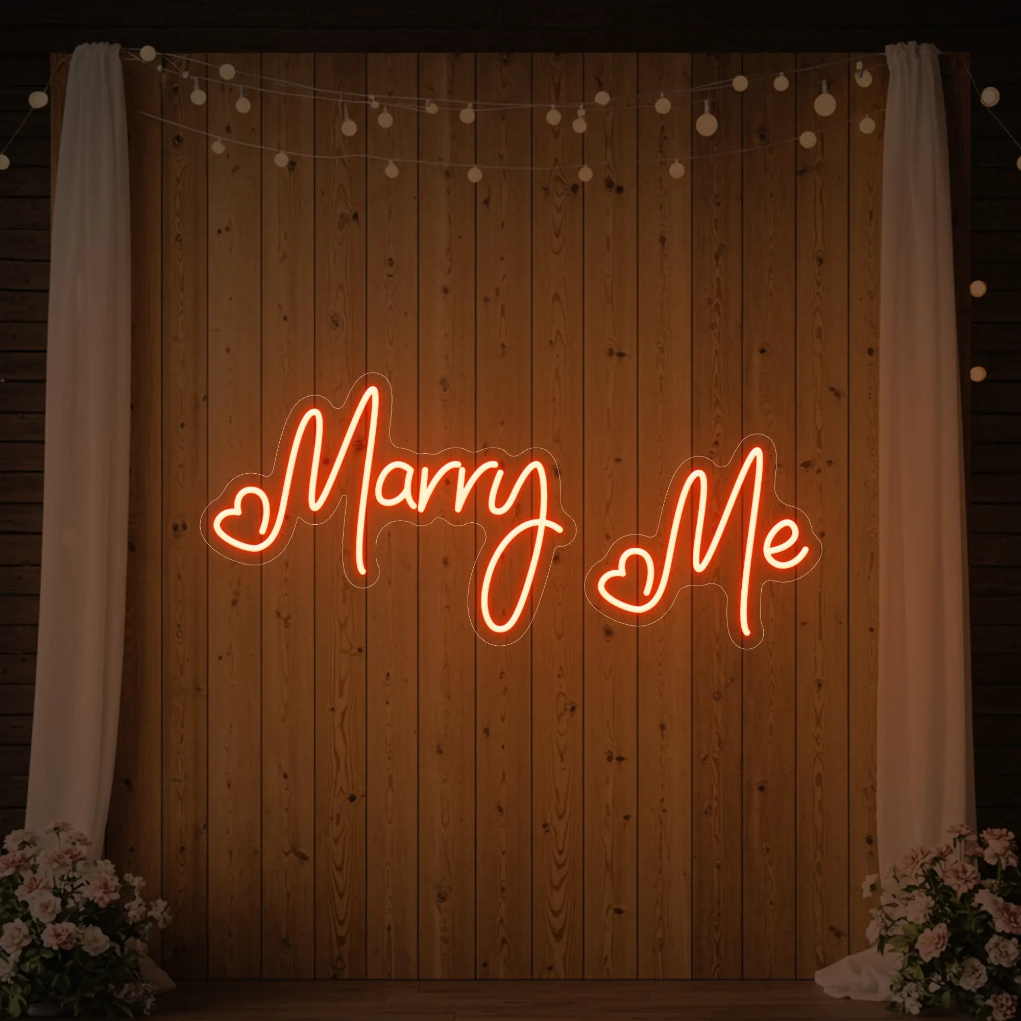 Photo of the 'Marry Me' neon sign glowing in golden yellow against a styled interior wall.
