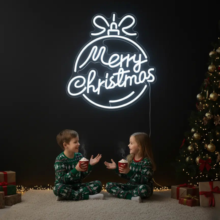Photo of the 'Merry Christmas in a Christmas Ball' neon sign glowing in cool white against a styled interior wall.