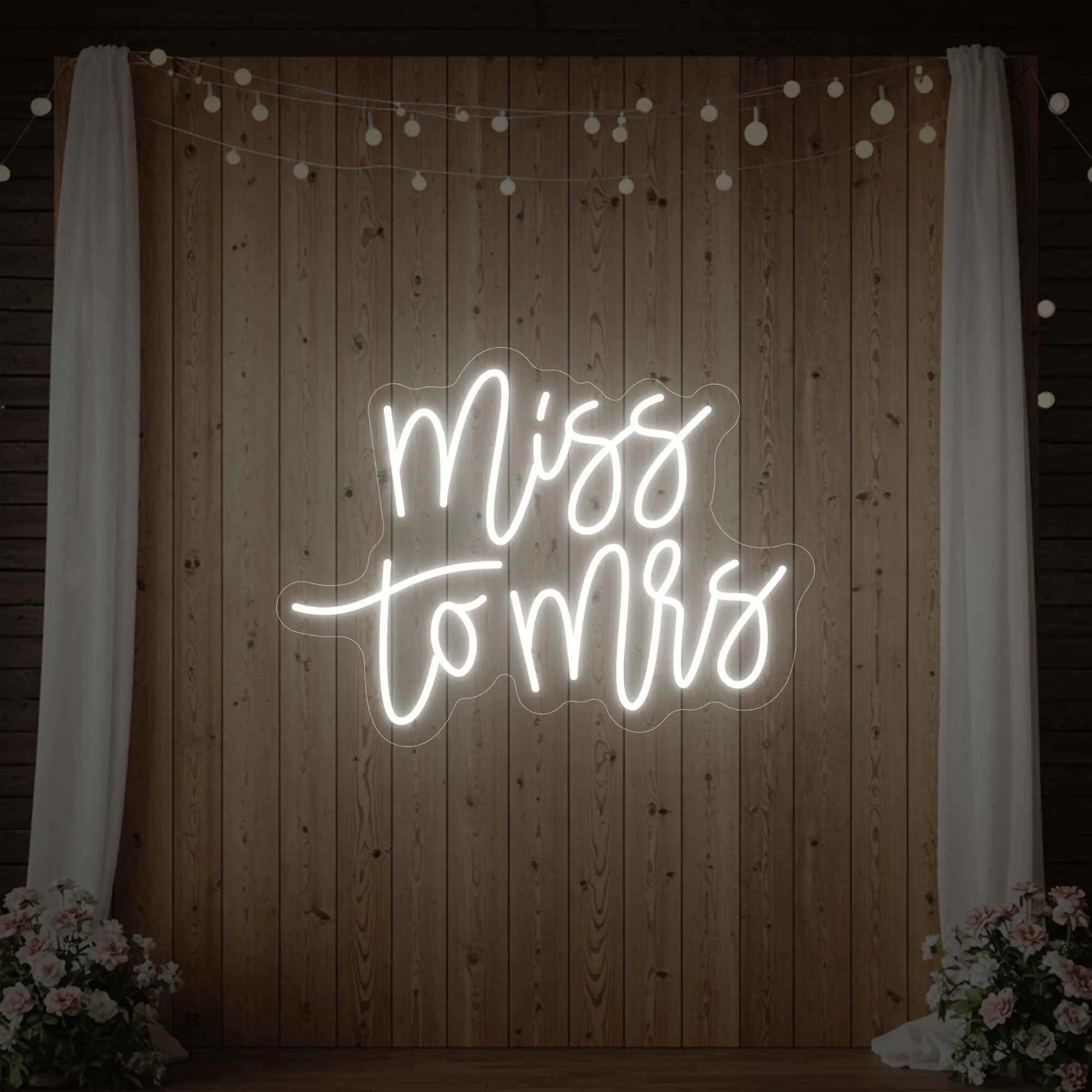 Photo of the 'Miss to Mrs' neon sign glowing in cool white against a styled interior wall.
