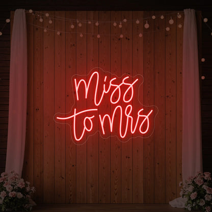 Photo of the 'Miss to Mrs' neon sign glowing in red against a styled interior wall.
