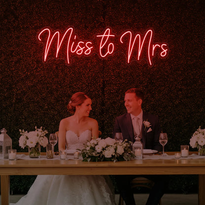 Photo of the 'Miss to Mrs' neon sign glowing in red against a styled interior wall.