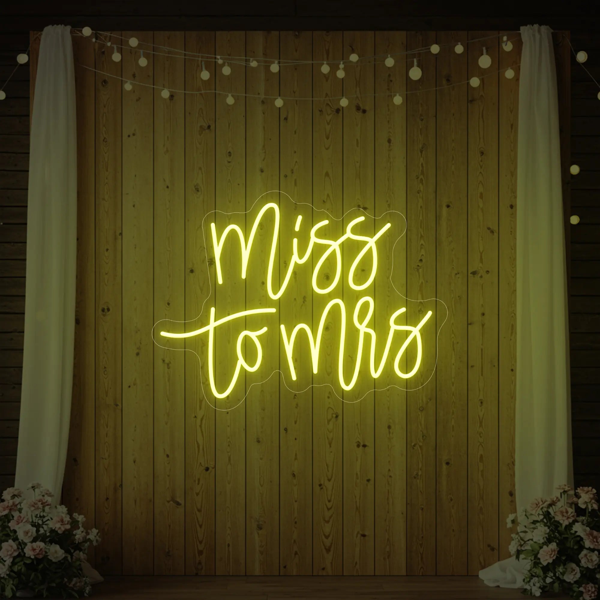 Photo of the 'Miss to Mrs' neon sign glowing in lemon yellow against a styled interior wall.