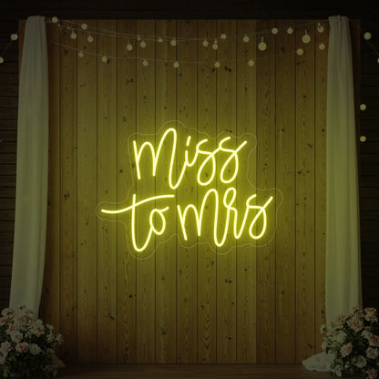 Photo of the 'Miss to Mrs' neon sign glowing in lemon yellow against a styled interior wall.