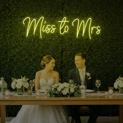 Photo of the 'Miss to Mrs' neon sign glowing in lemon yellow against a styled interior wall.