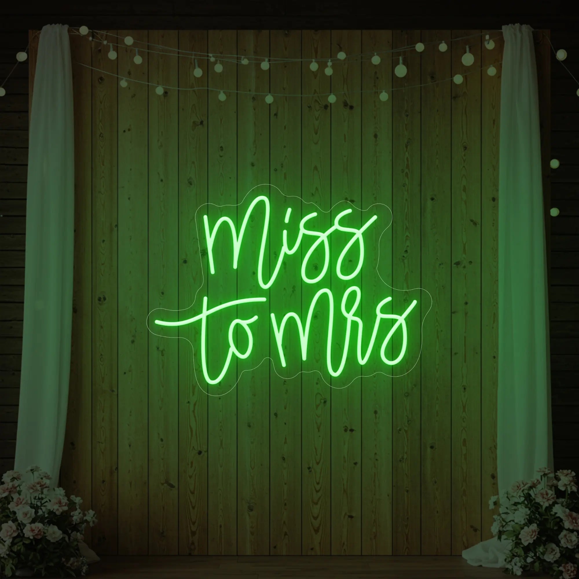 Photo of the 'Miss to Mrs' neon sign glowing in green against a styled interior wall.