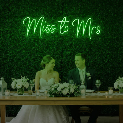 Photo of the 'Miss to Mrs' neon sign glowing in green against a styled interior wall.
