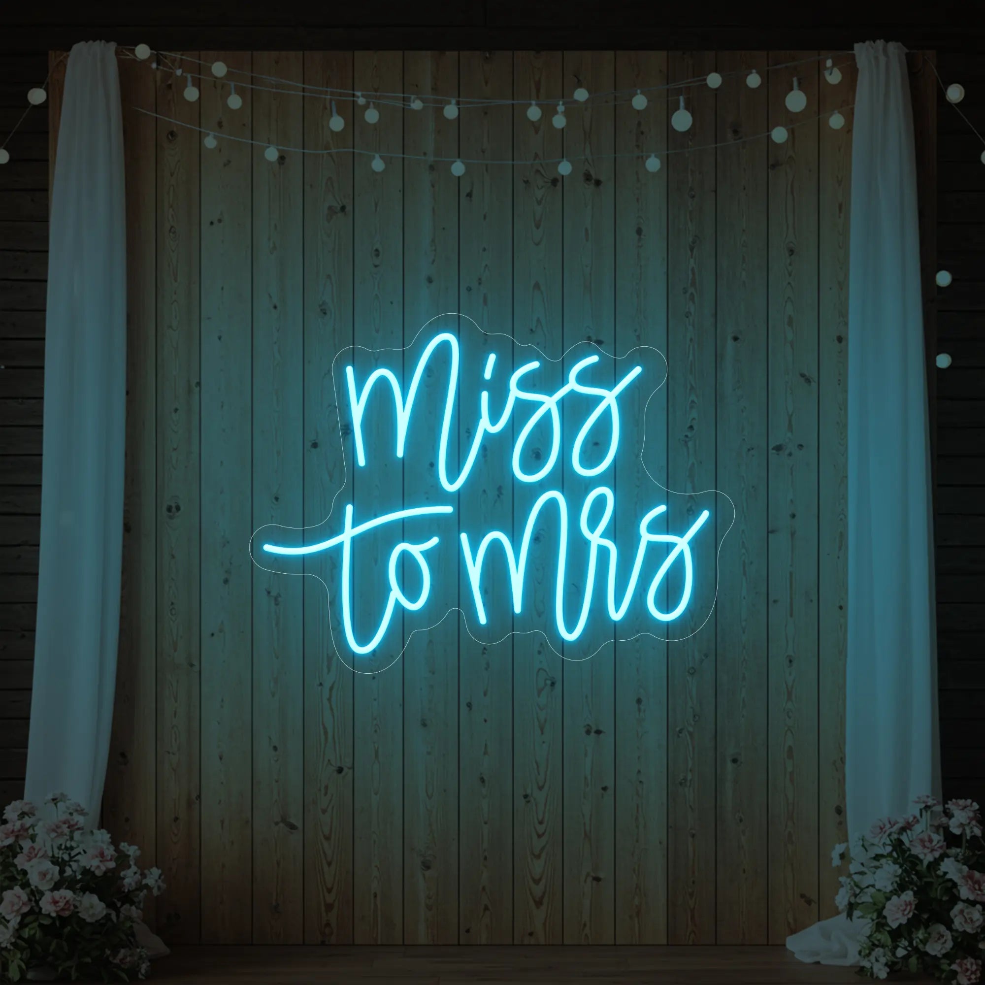 Photo of the 'Miss to Mrs' neon sign glowing in ice blue against a styled interior wall.