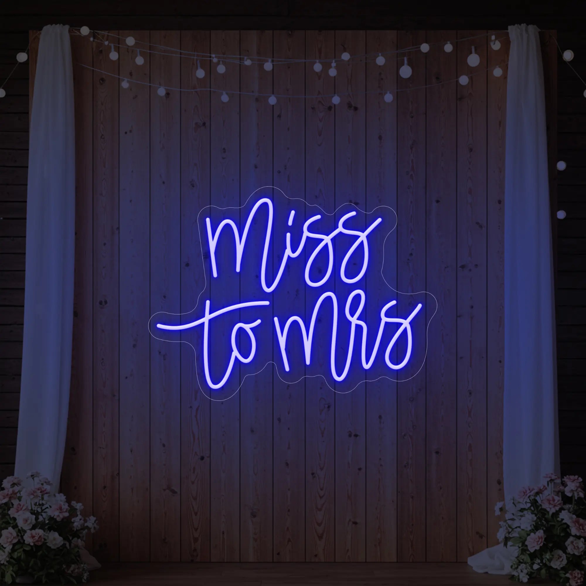 Photo of the 'Miss to Mrs' neon sign glowing in deep blue against a styled interior wall.