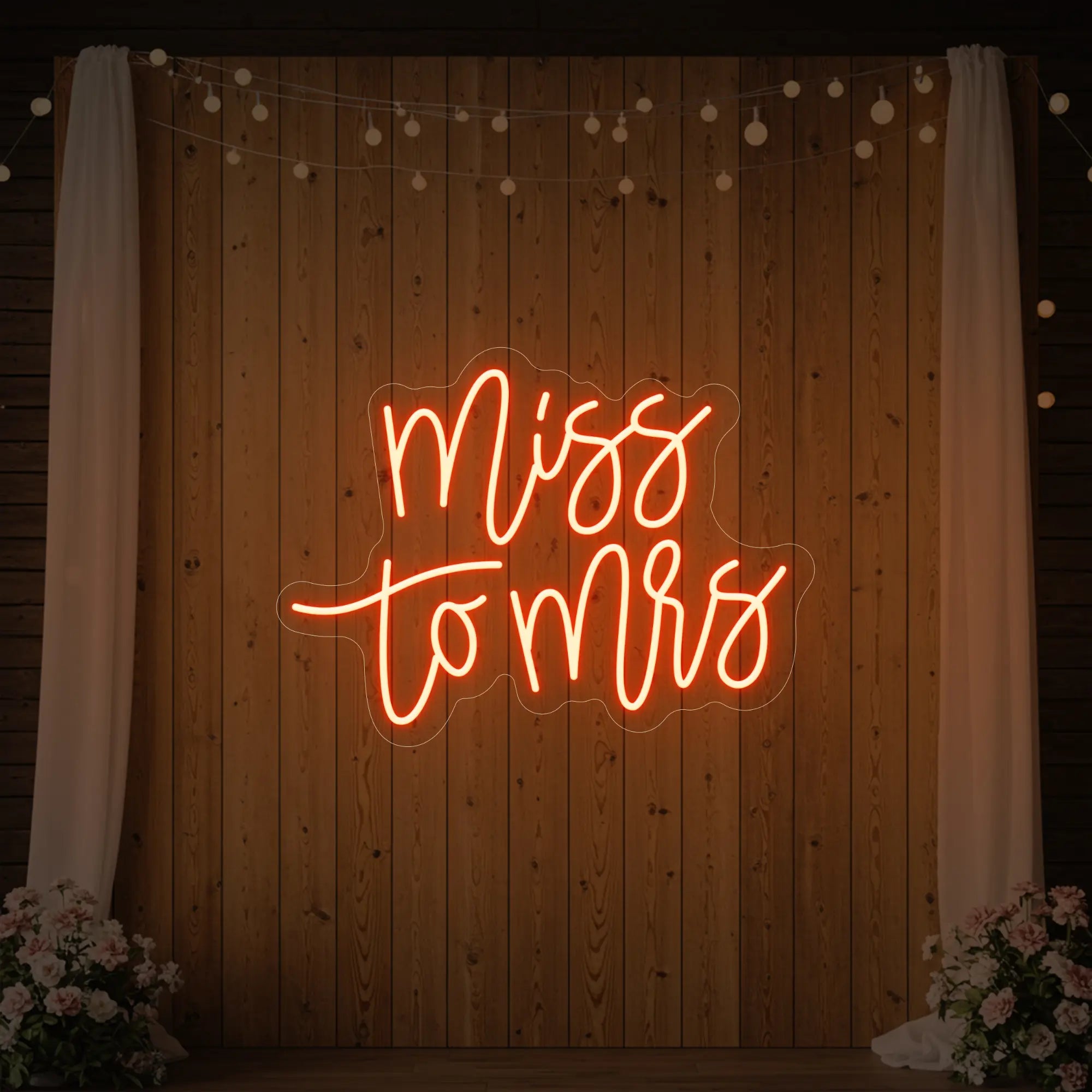 Photo of the 'Miss to Mrs' neon sign glowing in golden yellow against a styled interior wall.