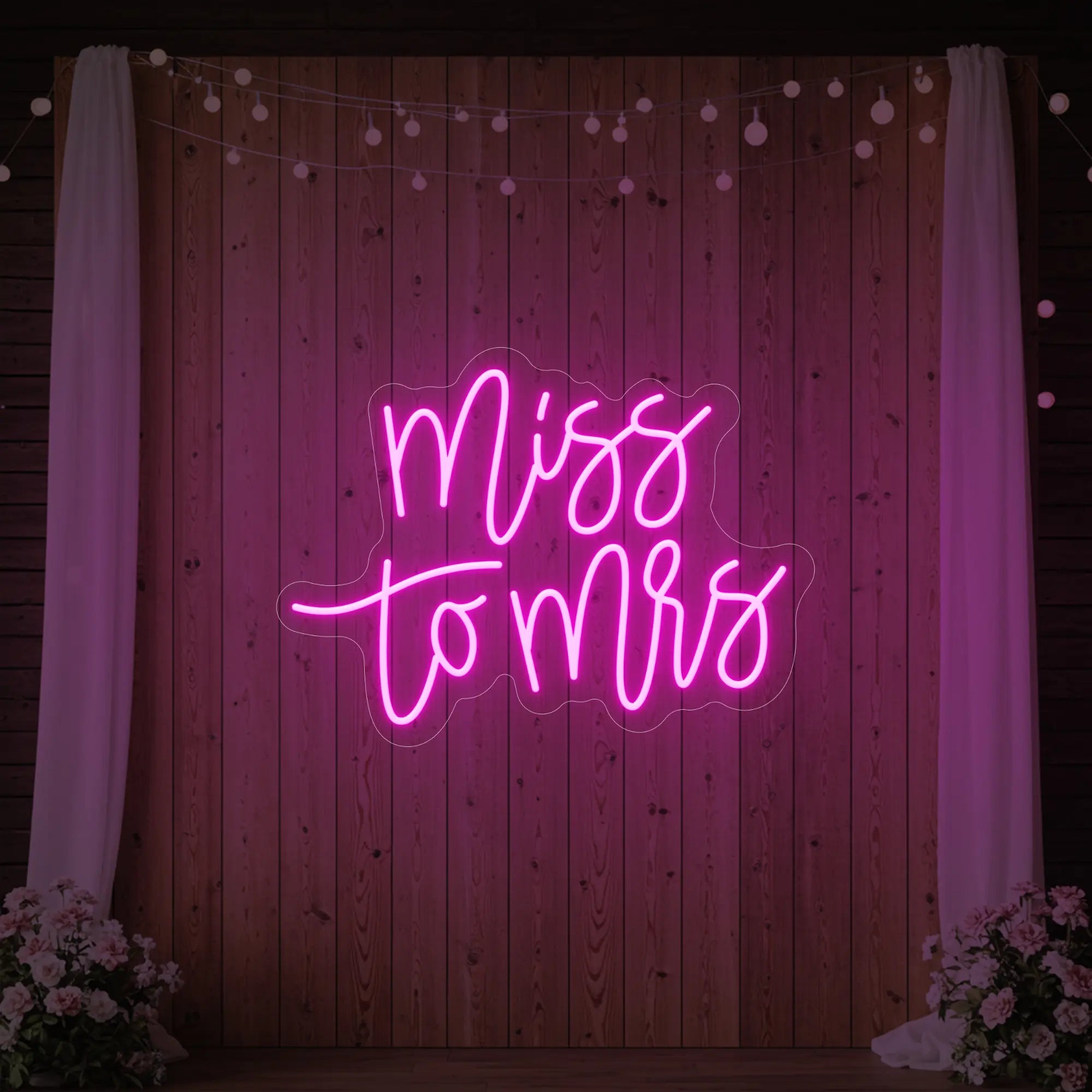 Photo of the 'Miss to Mrs' neon sign glowing in light pink against a styled interior wall.