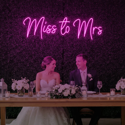 Photo of the 'Miss to Mrs' neon sign glowing in light pink against a styled interior wall.