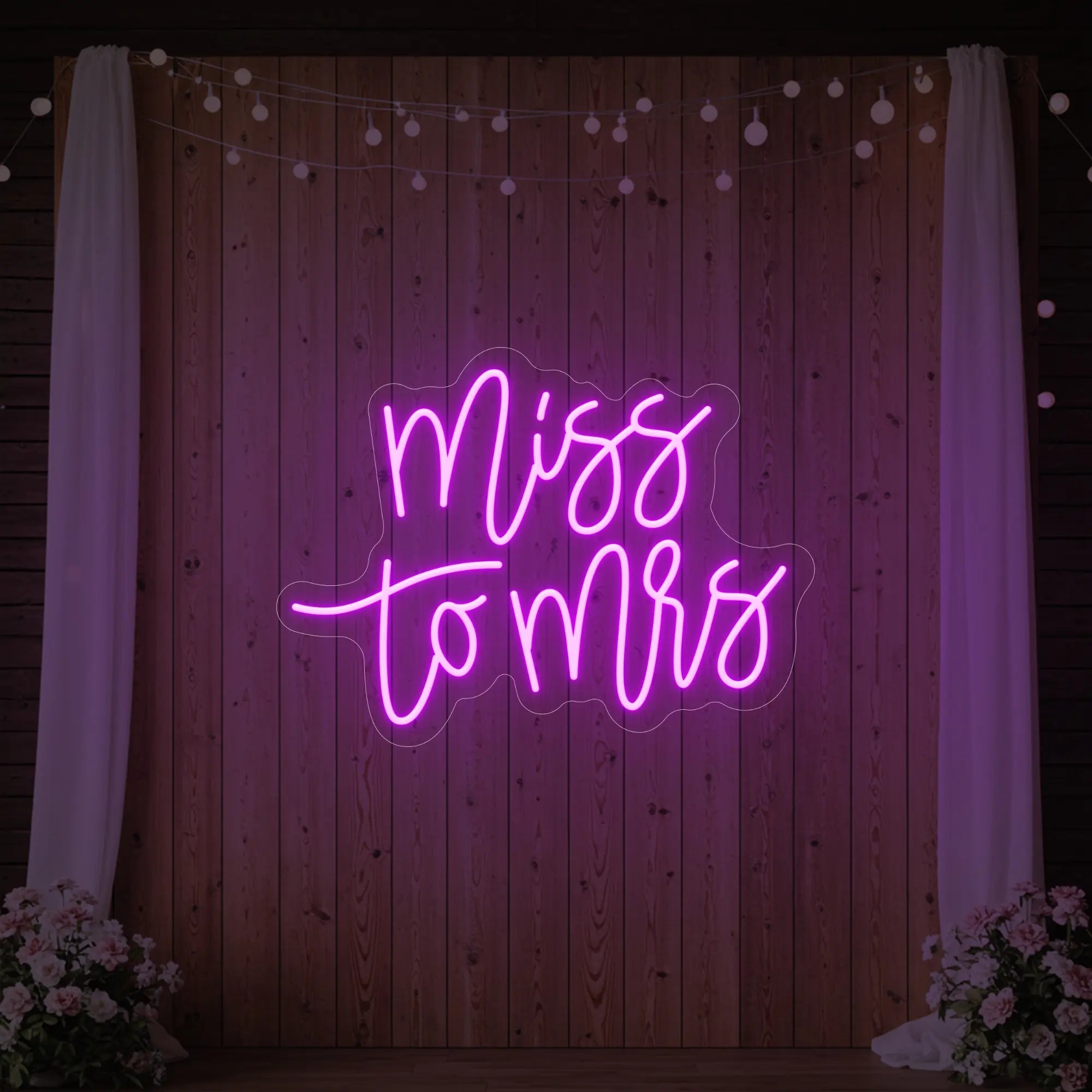 Photo of the 'Miss to Mrs' neon sign glowing in deep pink against a styled interior wall.