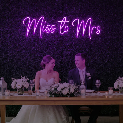 Photo of the 'Miss to Mrs' neon sign glowing in deep pink against a styled interior wall.