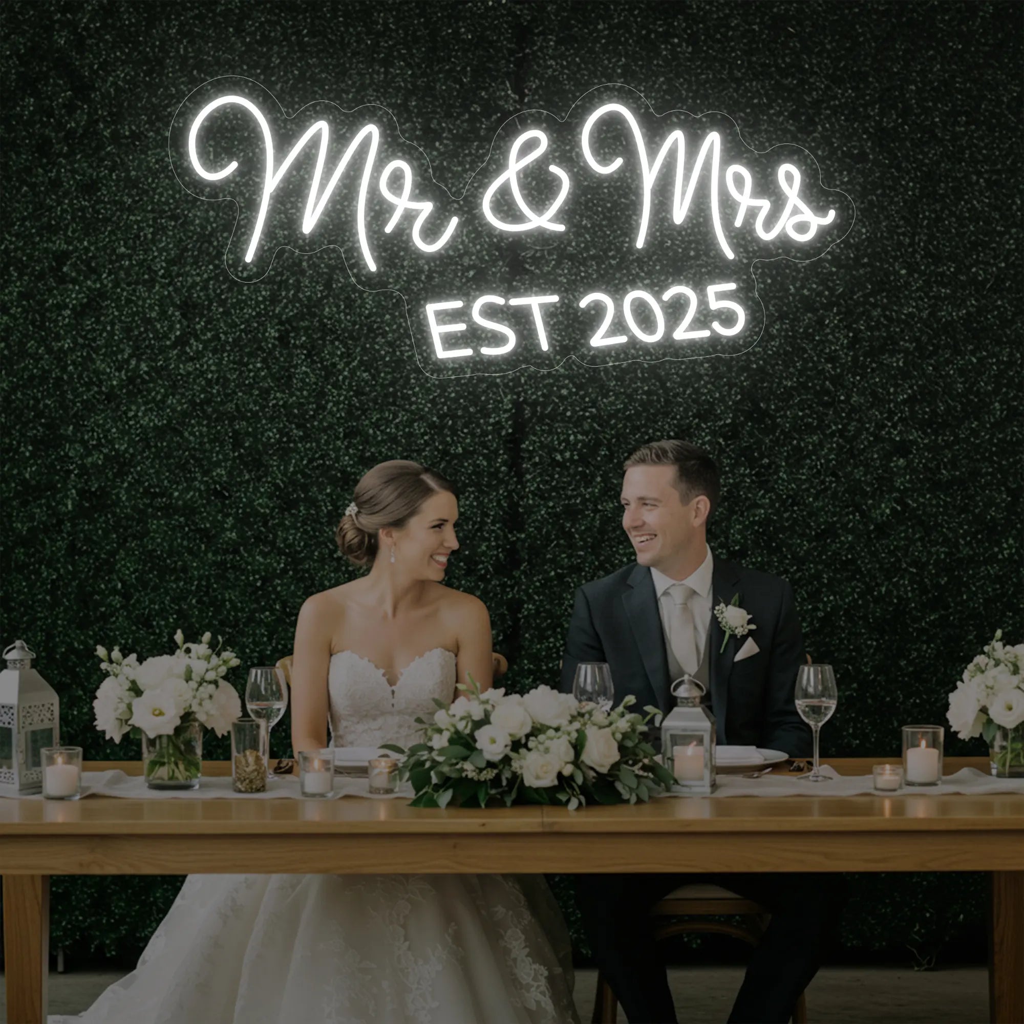 Photo of the 'Mr & Mrs EST' neon sign glowing in cool white against a styled interior wall.