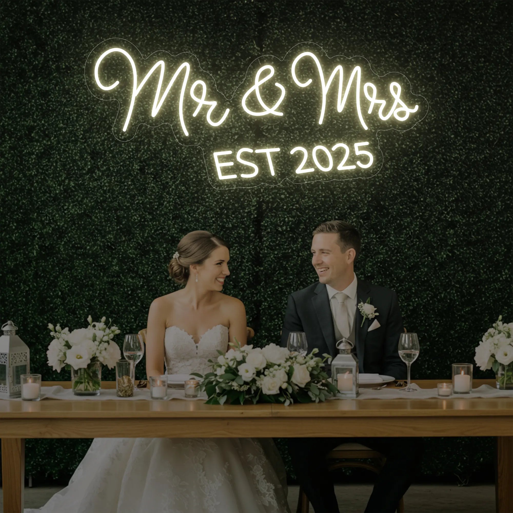 Photo of the 'Mr & Mrs EST' neon sign glowing in warm white against a styled interior wall.