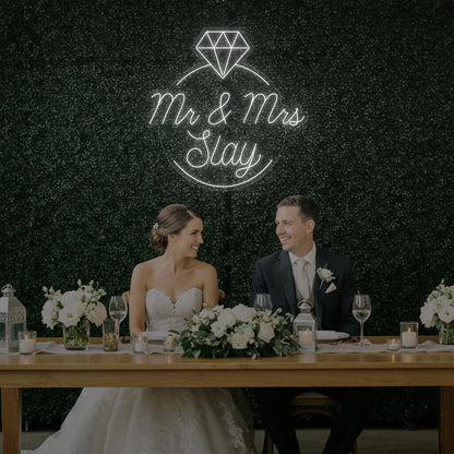 Photo of the 'Mr & Mrs EST' neon sign glowing in cool white against a styled interior wall.
