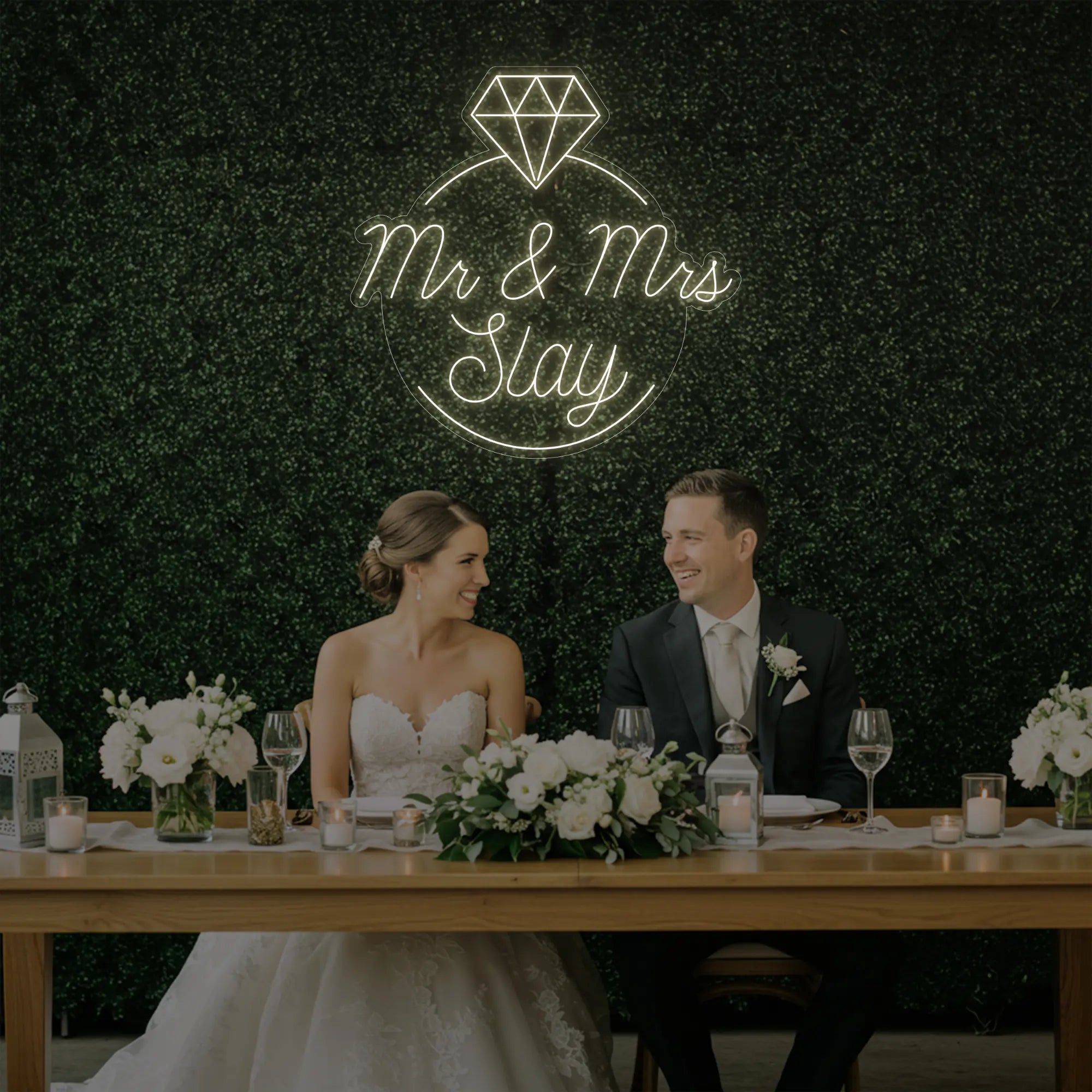 Photo of the 'Mr & Mrs EST' neon sign glowing in warm white against a styled interior wall.