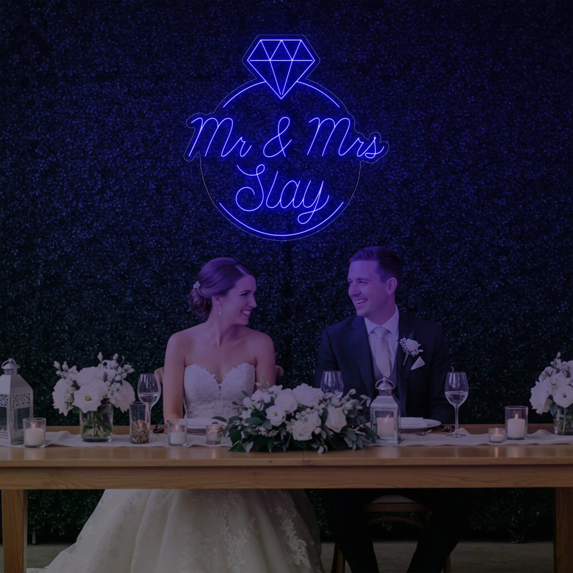 Photo of the 'Mr & Mrs EST' neon sign glowing in deep blue against a styled interior wall.