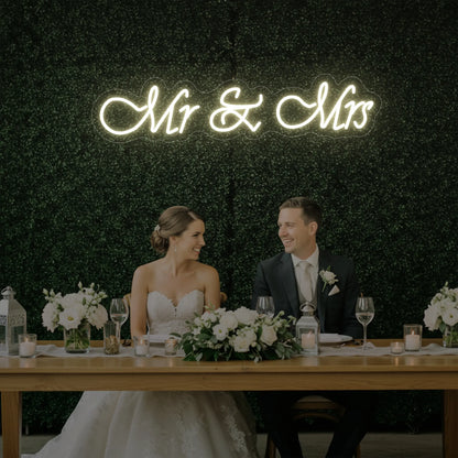 Photo of the 'Mr & Mrs' neon sign glowing in warm white against a styled interior wall.