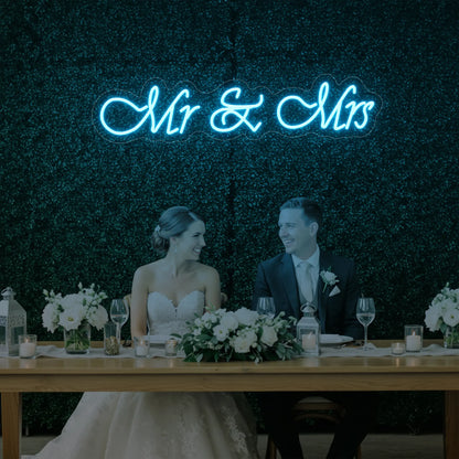 Photo of the 'Mr & Mrs' neon sign glowing in ice blue against a styled interior wall.