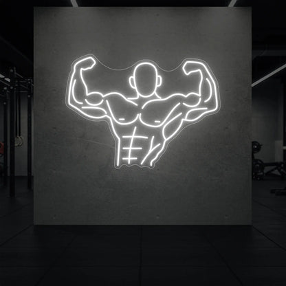 'Muscle Man (Torso-Up Flex)' neon sign glowing in cool white against a styled interior wall.