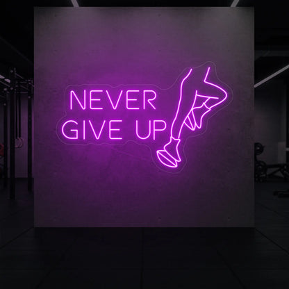  'NEVER GIVE UP' neon sign glowing in deep pink against a styled interior wall.