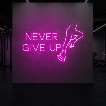 'NEVER GIVE UP' neon sign glowing in light pink against a styled interior wall.