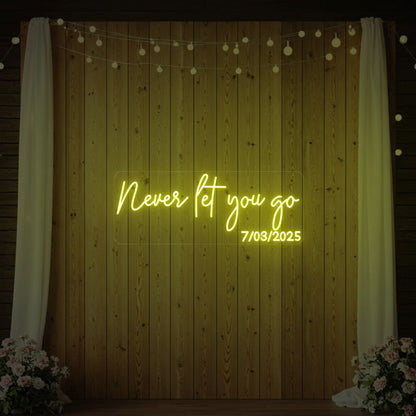 'Never Let You Go' neon sign glowing in lemon yellow against a styled interior wall.