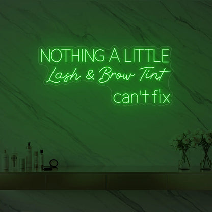 Photo of the 'Nothing a Little Lash & Brow Tint Can’t Fix' neon sign glowing in green against a styled interior wall.