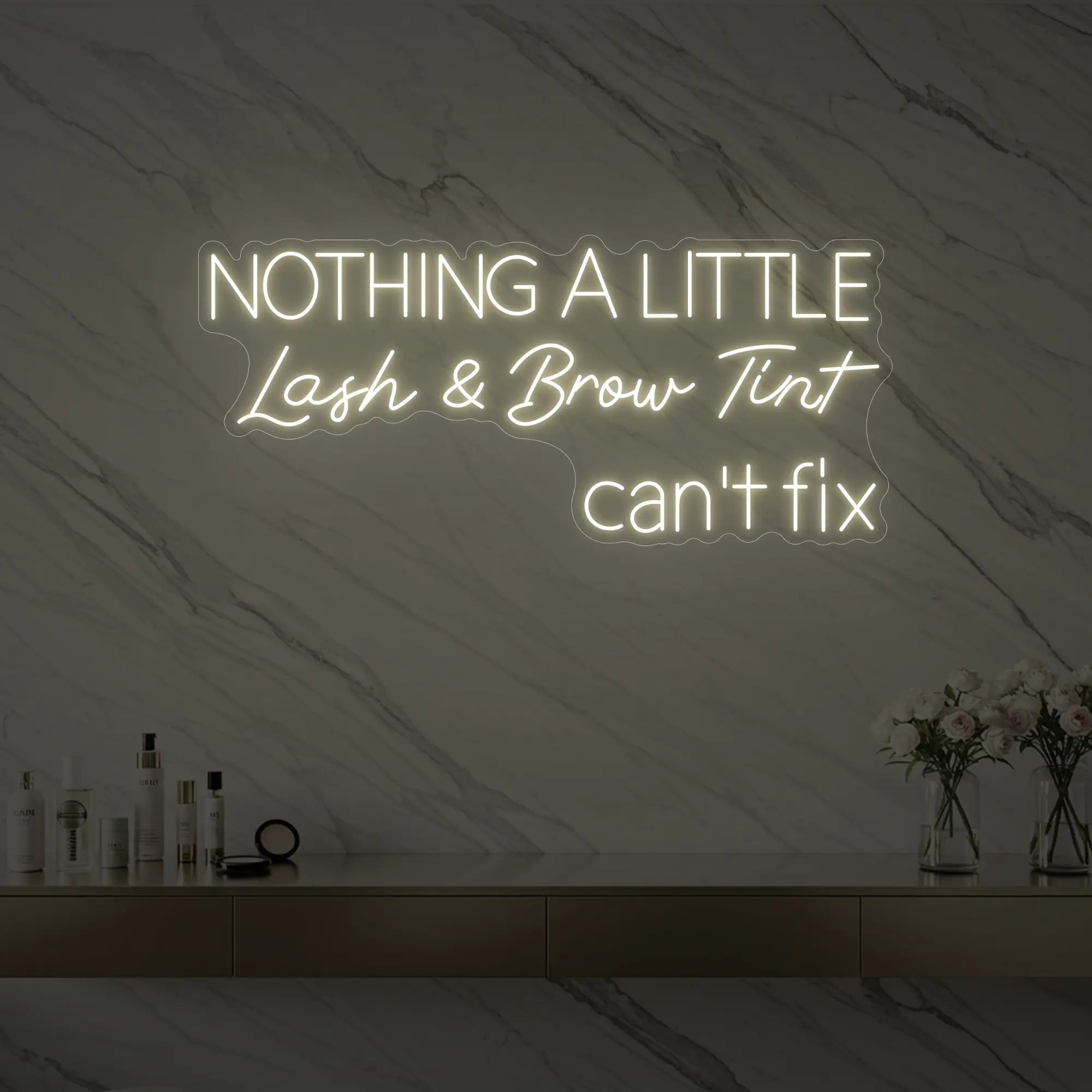 Photo of the 'Nothing a Little Lash & Brow Tint Can’t Fix' neon sign glowing in warm white against a styled interior wall.