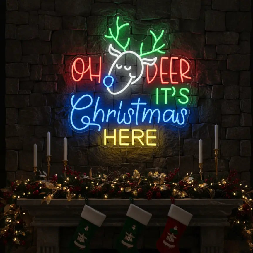 Photo of the 'Oh Deer It's Christmas Here' neon sign glowing in cool white against a styled interior wall.