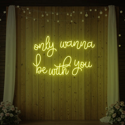 Photo of the 'Only Wanna Be With You' neon sign glowing in lemon yellow against a styled interior wall.