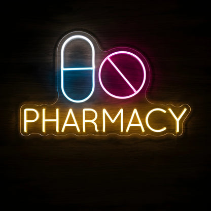 Pharmacy Pills LED Neon Sign featuring a blue and white capsule, pink round tablet, and yellow PHARMACY lettering on a dark wooden wall.
